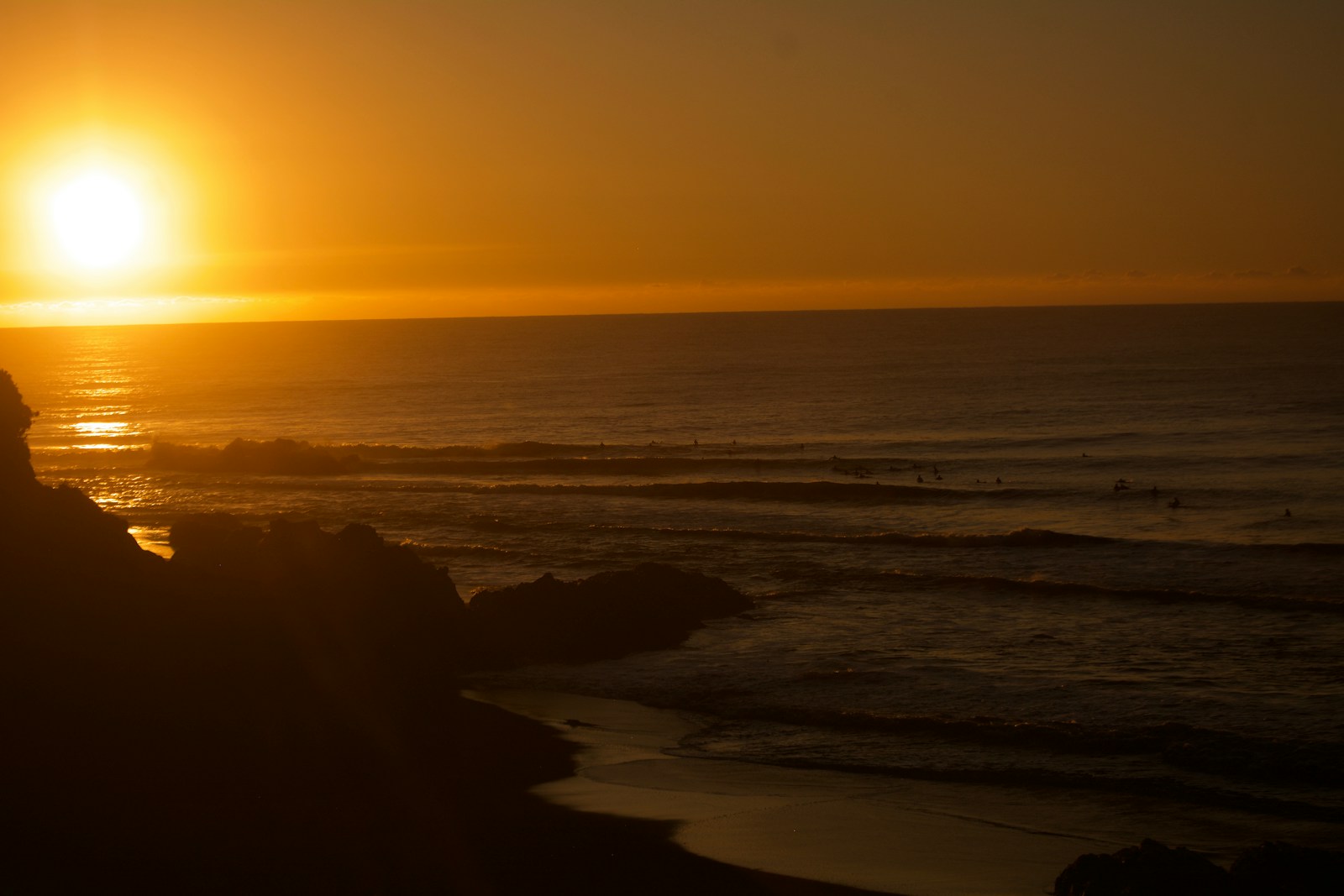 Sunset casts an orange glow over the ocean.
